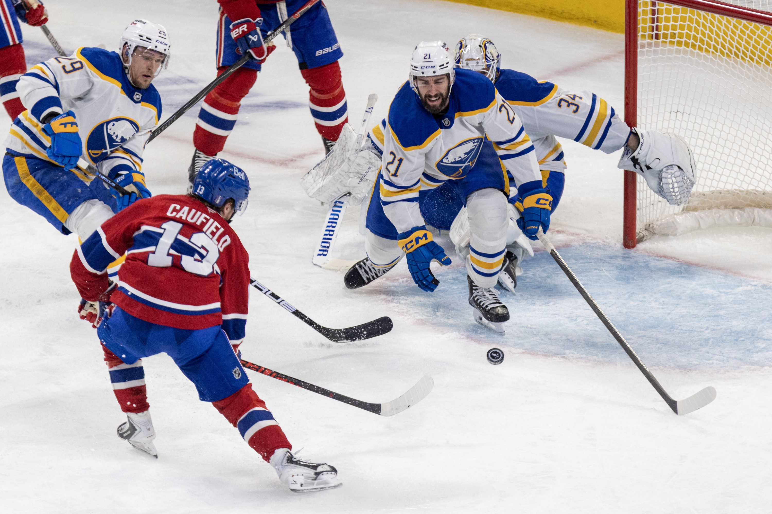 Montreal Canadiens' Cole Caufield shoots the puck past Buffalo Sabres' Beck Malenstyn, Conor Timmins and goalie Alex Lyon for a goal.
