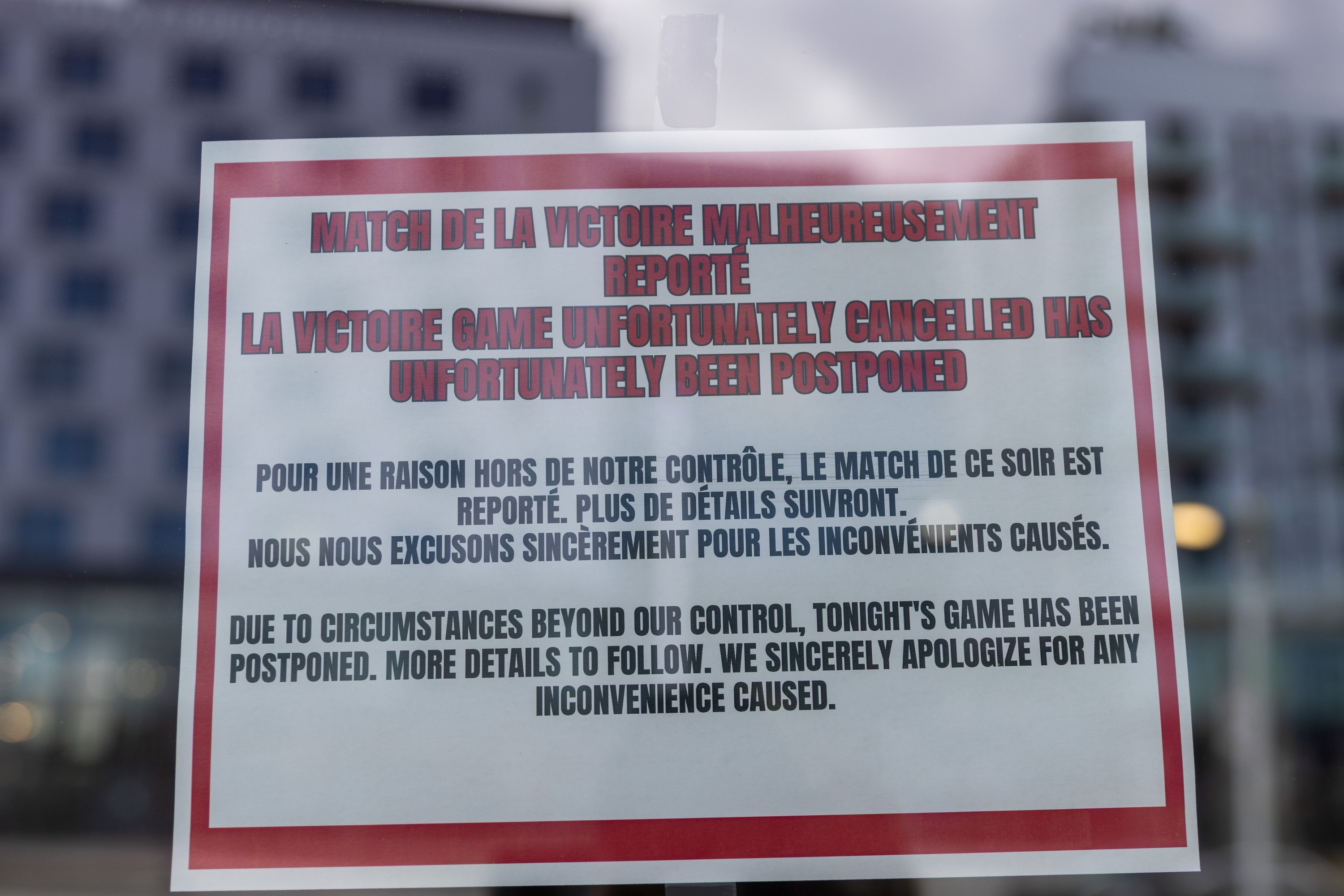 A sign taped to a glass window reads in English and French that a Victoire game has 'unfortunately been postponed'