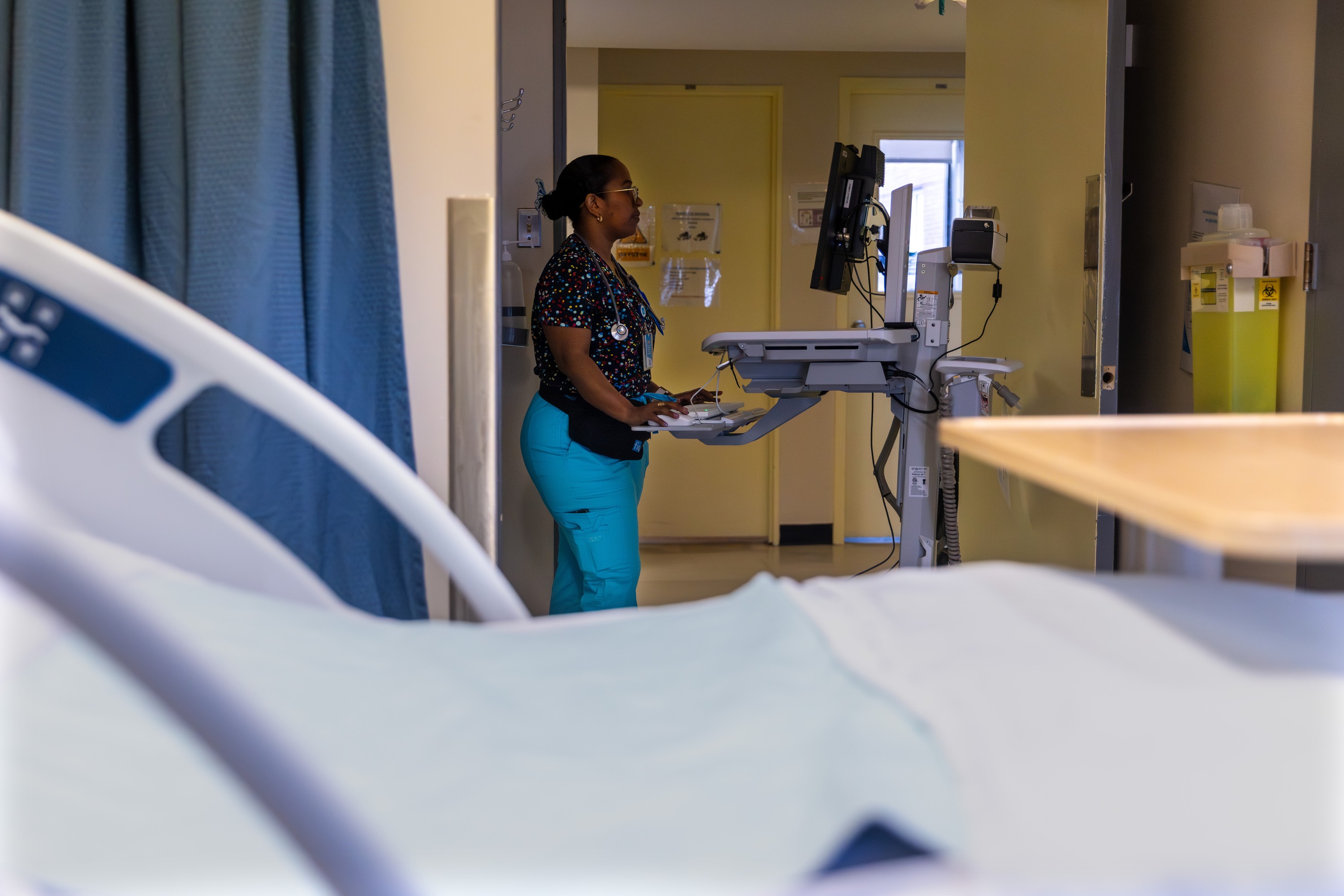 Nurse stands at workstation computer screen