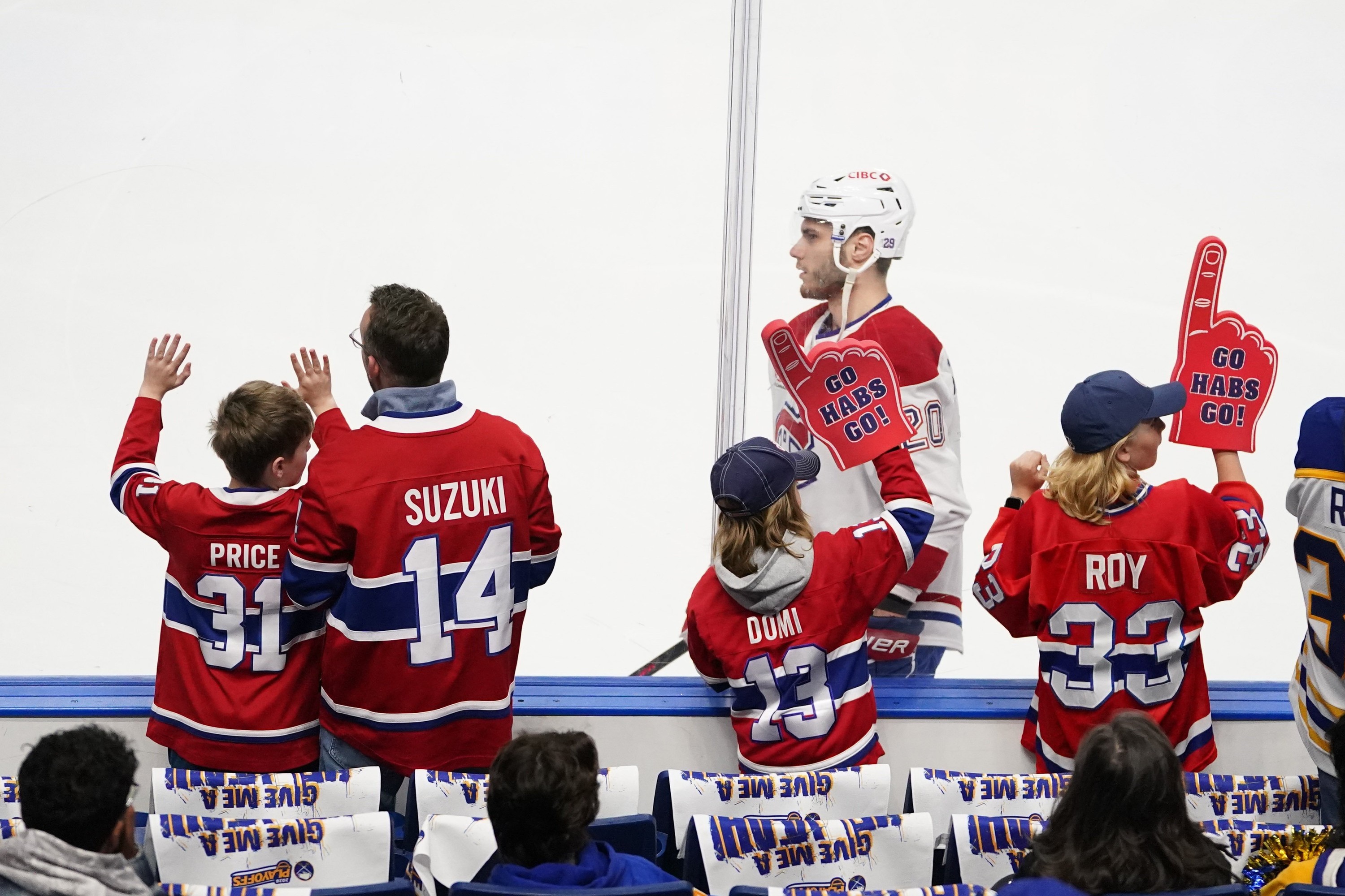 Children in Montreal Canadiens jerseys watching hockey players warm up