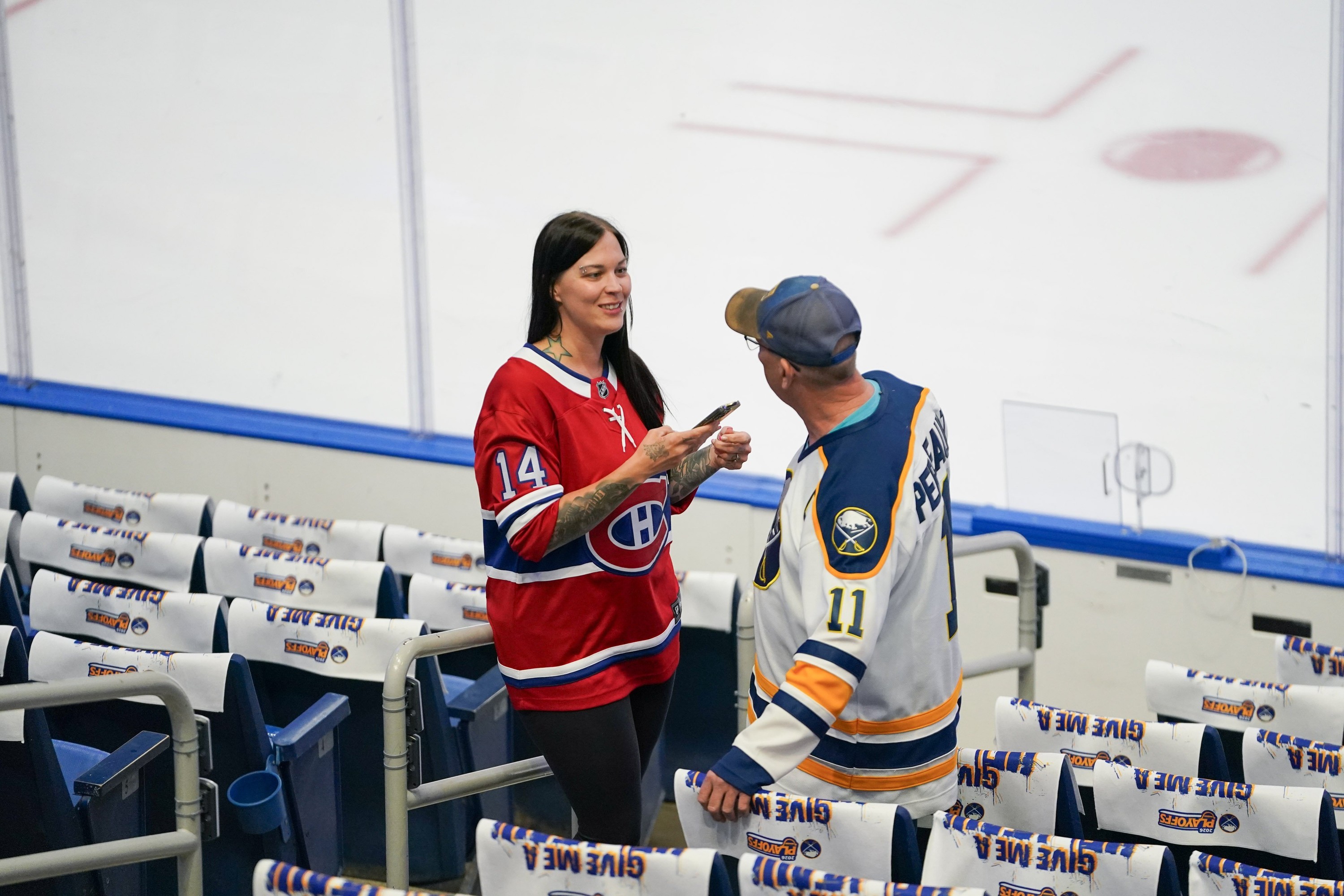 Woman in Canadiens Jersey speaking to man in Sabres jersey at hockey rink