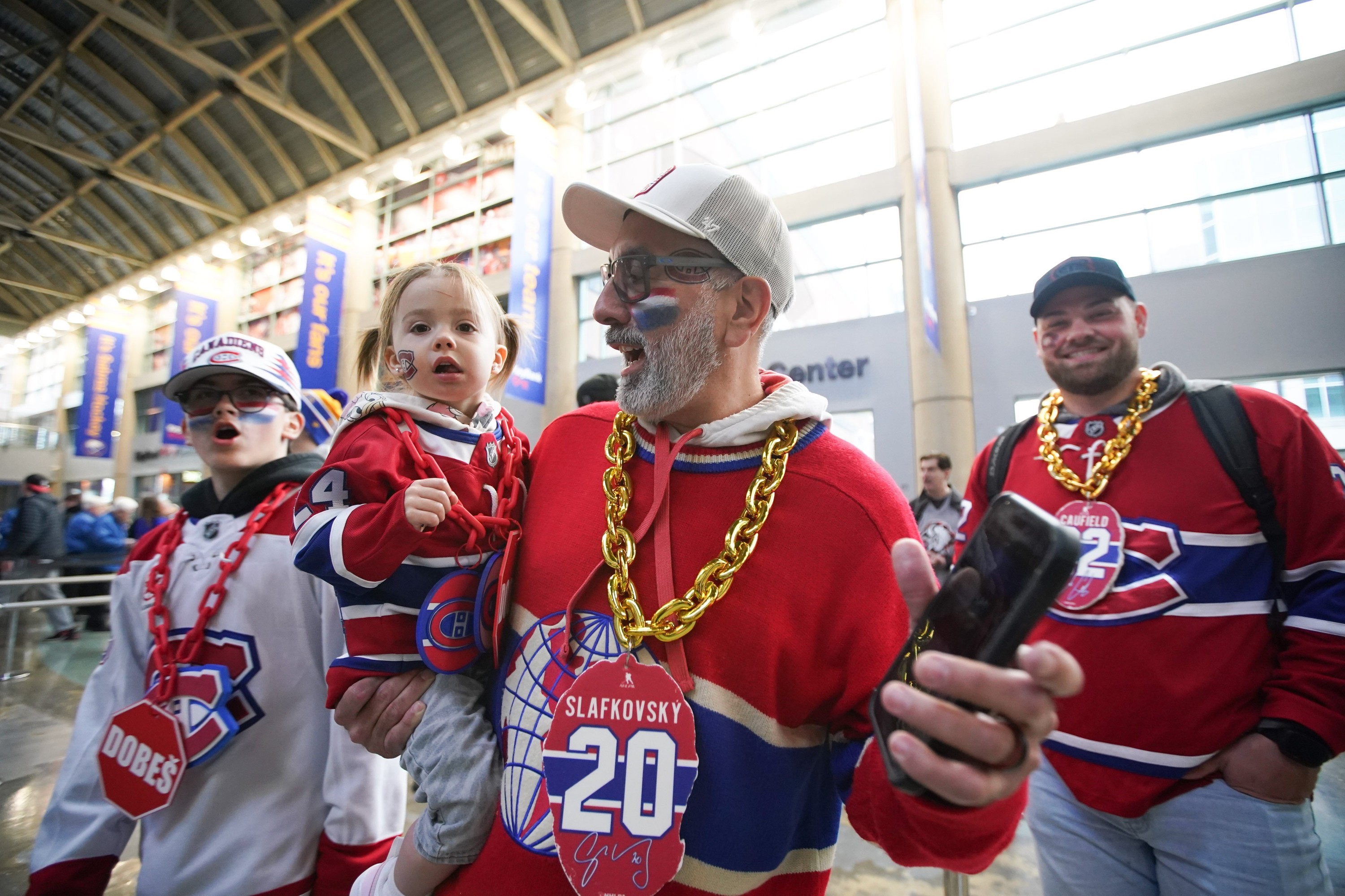 Man wearing Canadiens jersey holding child wearing Canadiens jersey