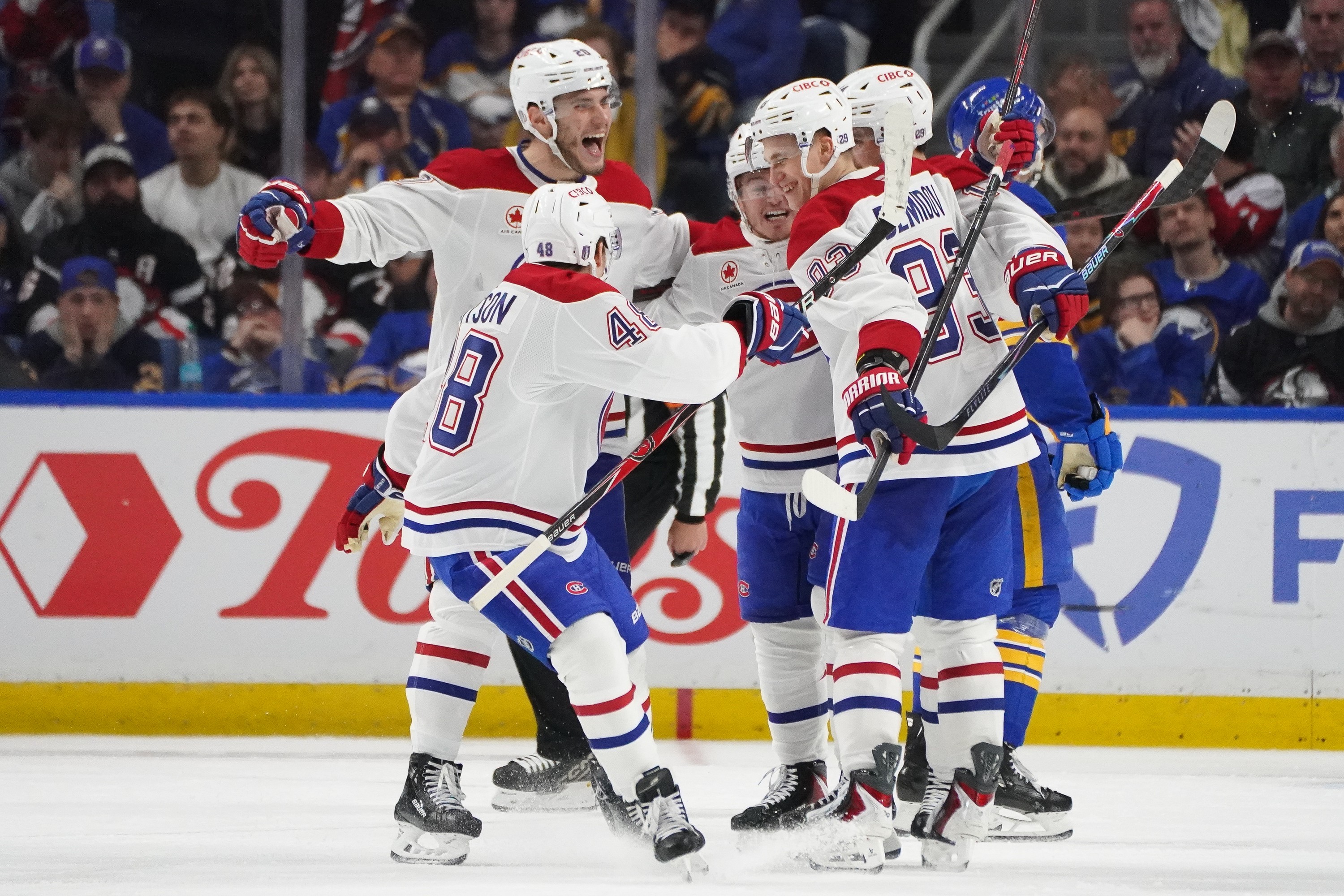 Hockey players gather on the ice to celebrate a goal.