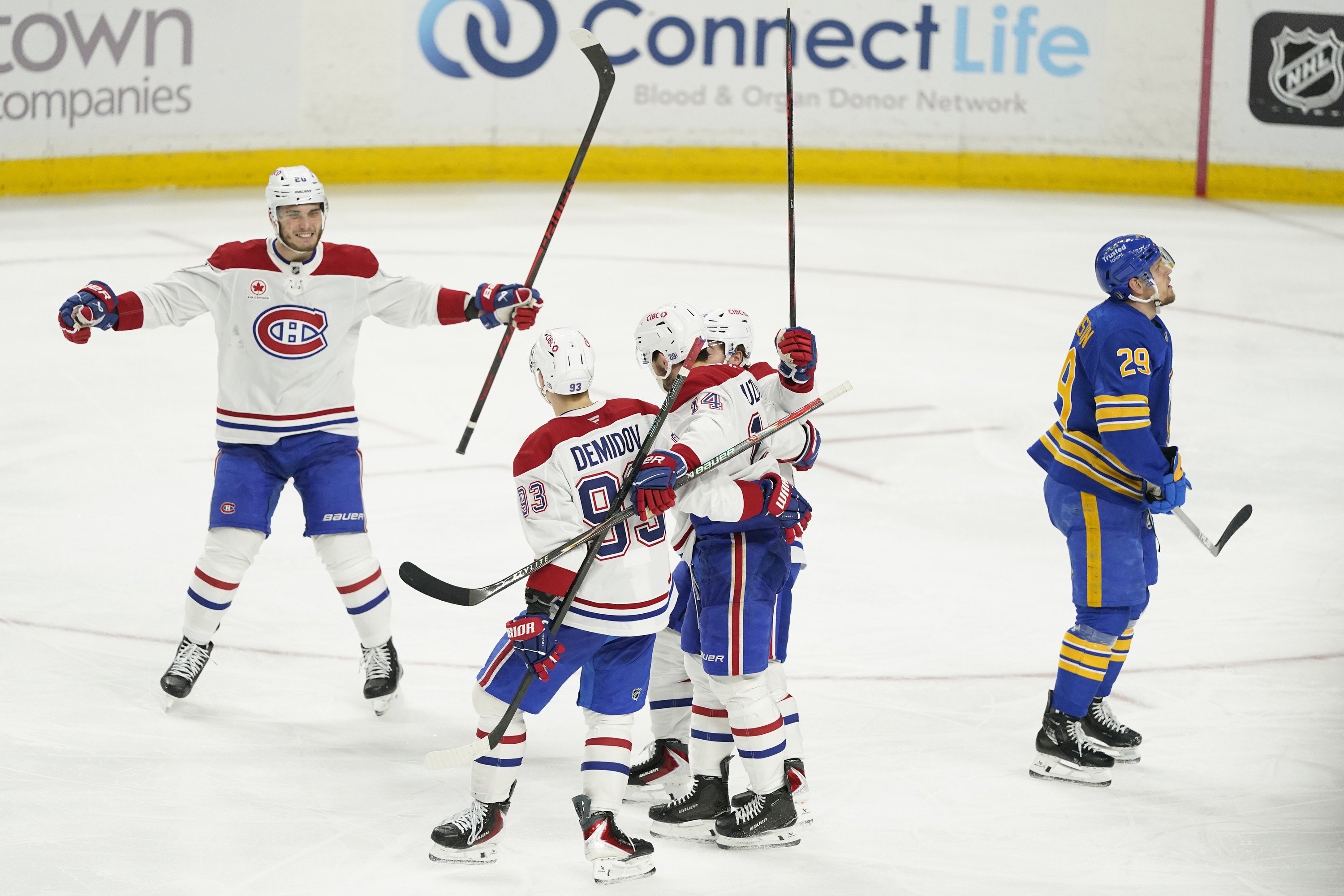 Hockey players gather on the ice to celebrate a goal.