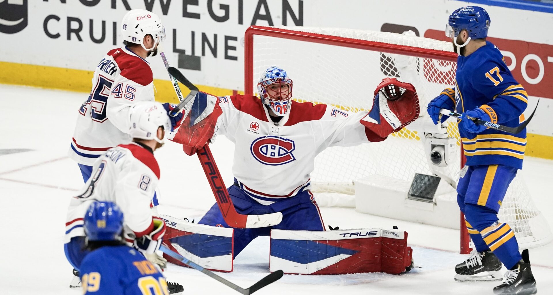 Hockey goaltender stretches wide to make a save.