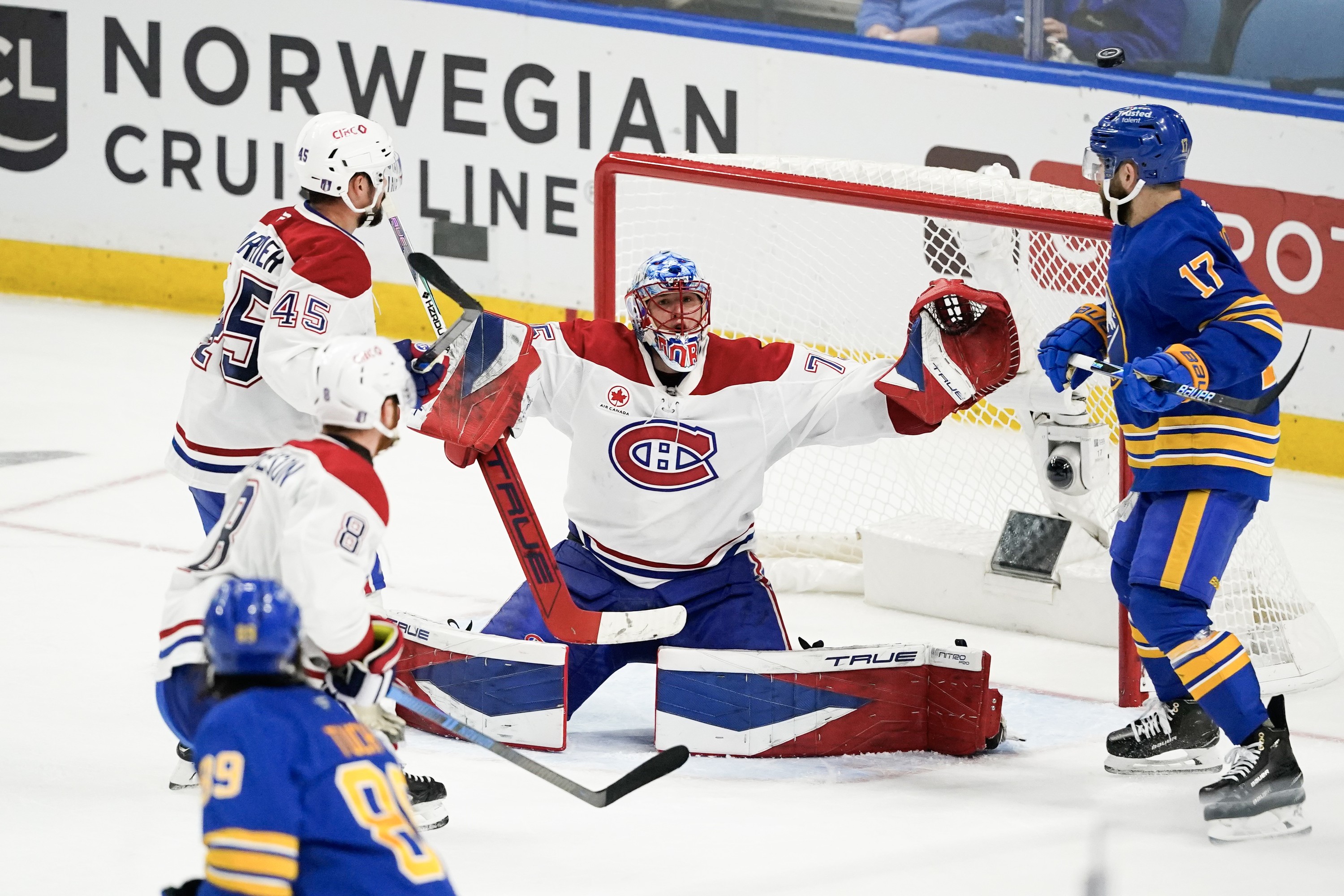 Hockey goaltender stretches wide to make a save.