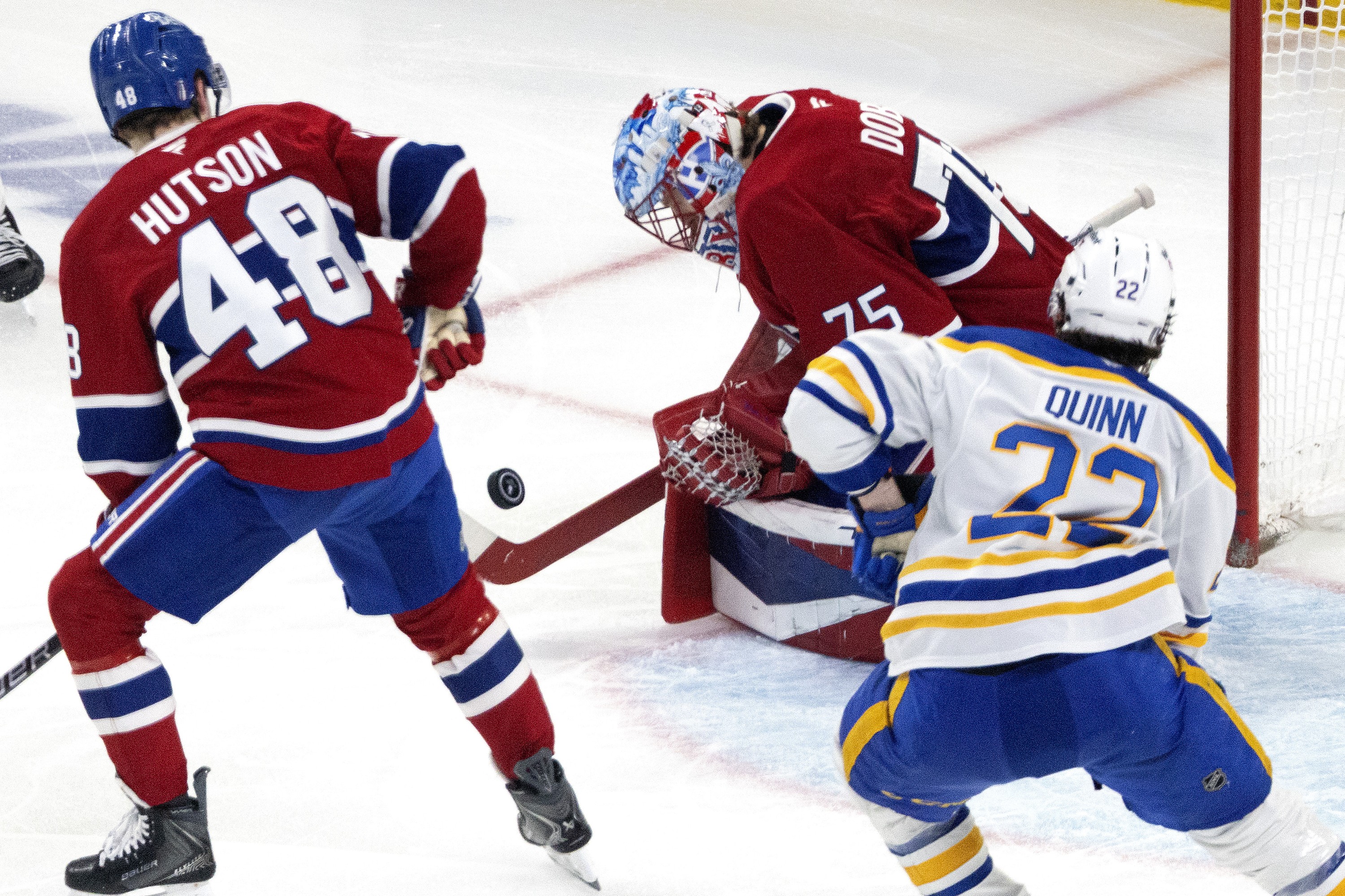 Montreal Canadiens goaltender Jakub Dobes allows a rebound as Canadiens defenceman Lane Hutson and Buffalo Sabres right wing Jack Quinn chase the play.