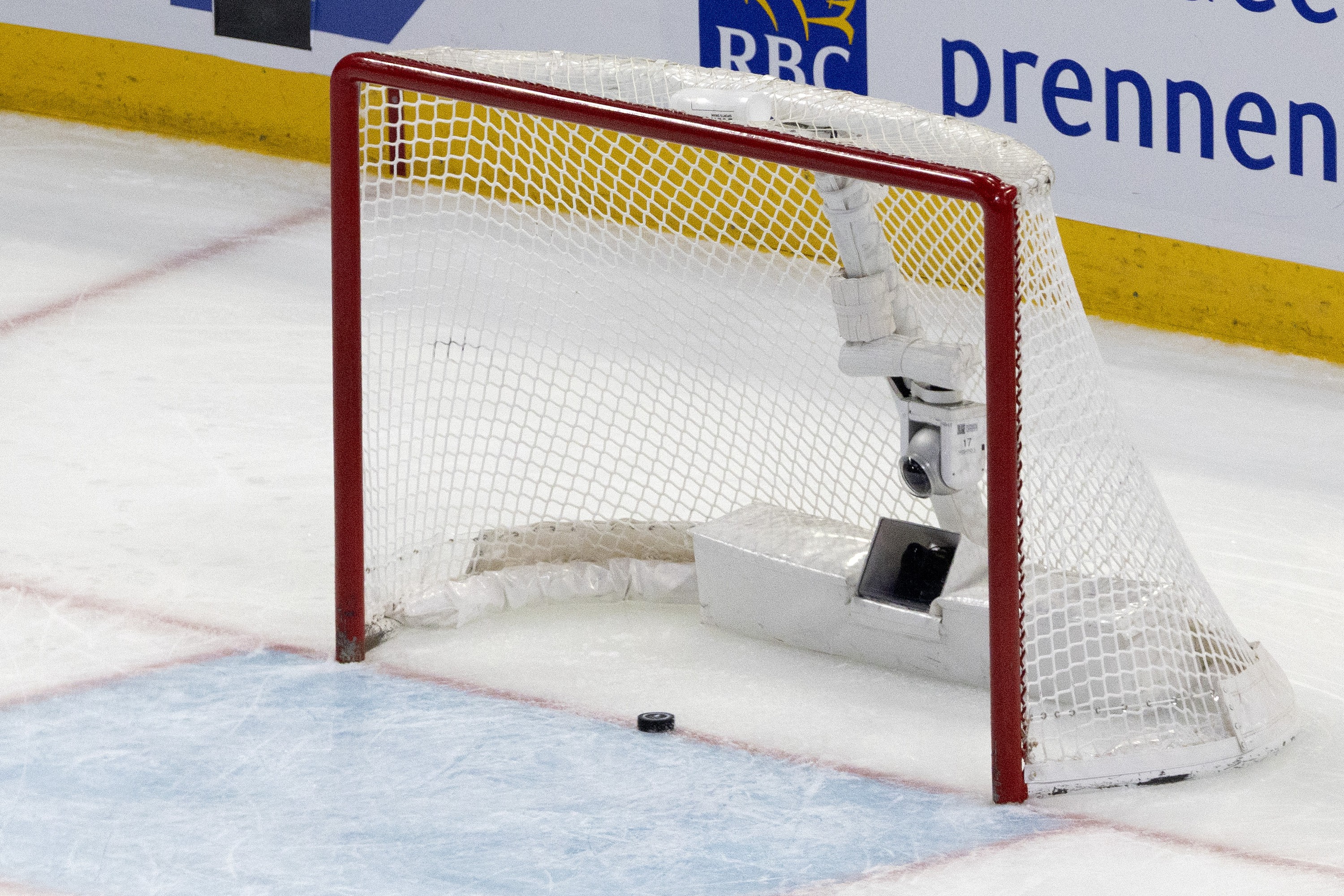 A puck sits on the red line in an empty hockey net at the Bell Centre.