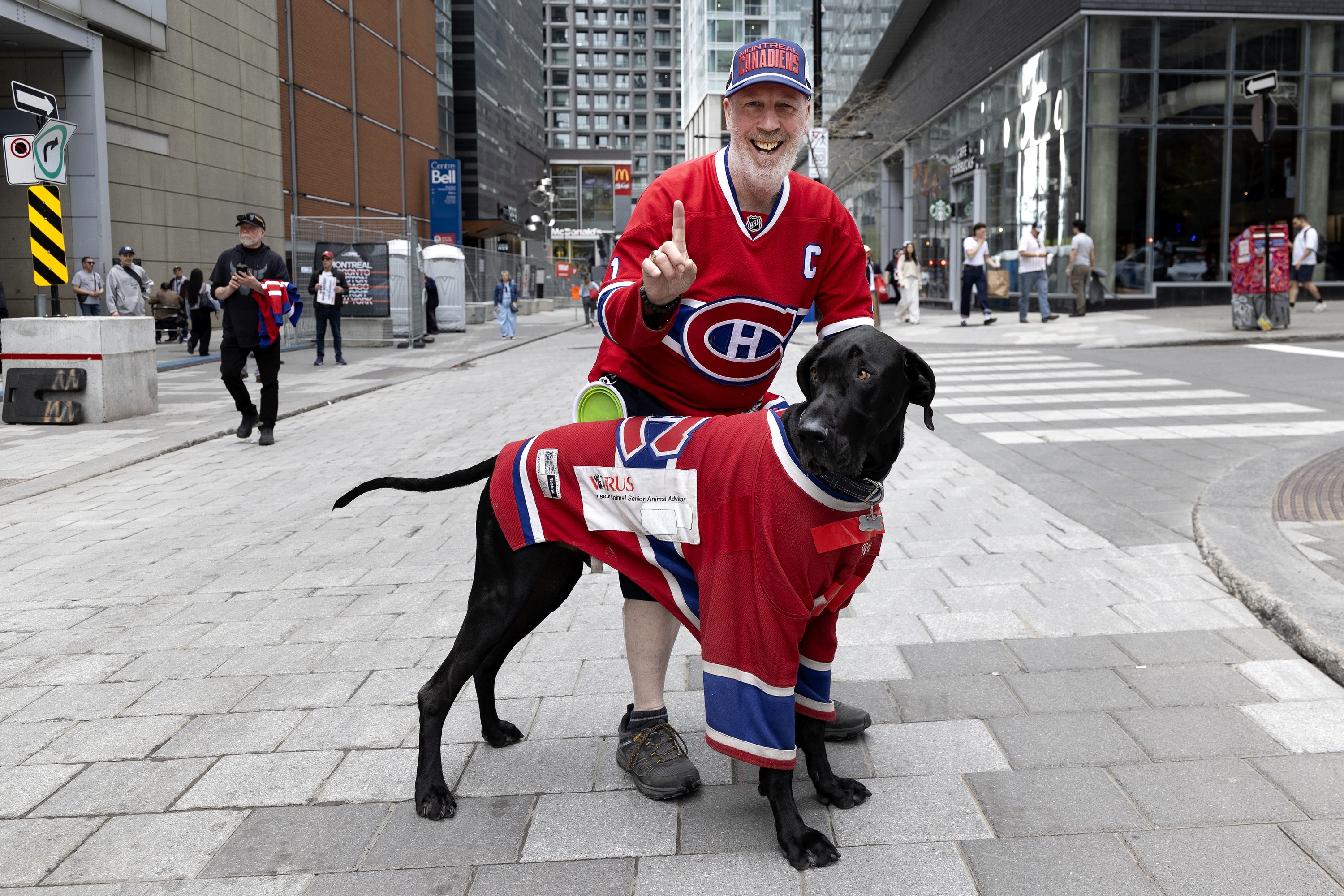 A Canadiens fan and his dog both dressed in team jerseys. 