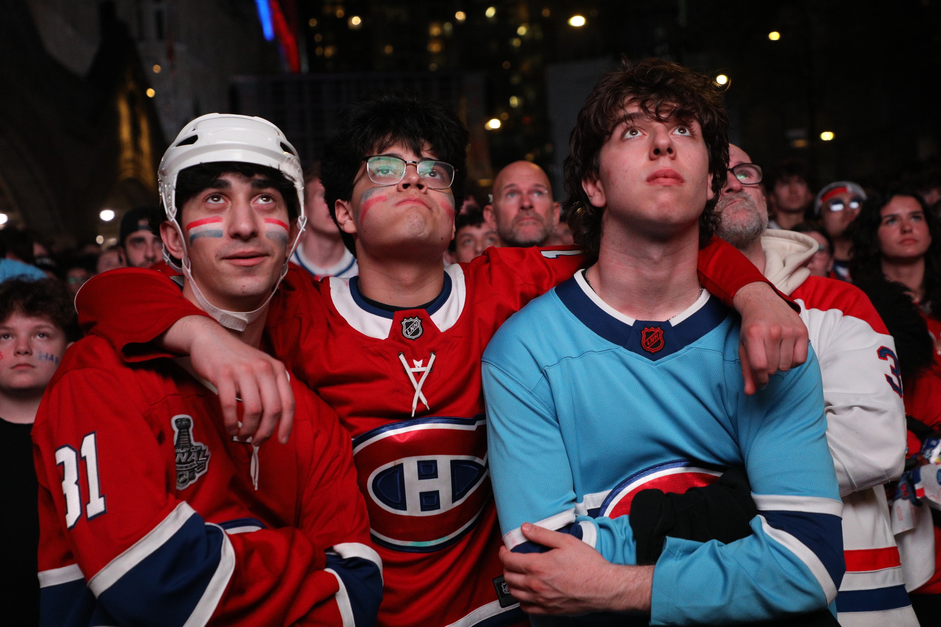 Close-up of disappointed Canadiens fans wearing Habs jerseys and looking forlorn.
