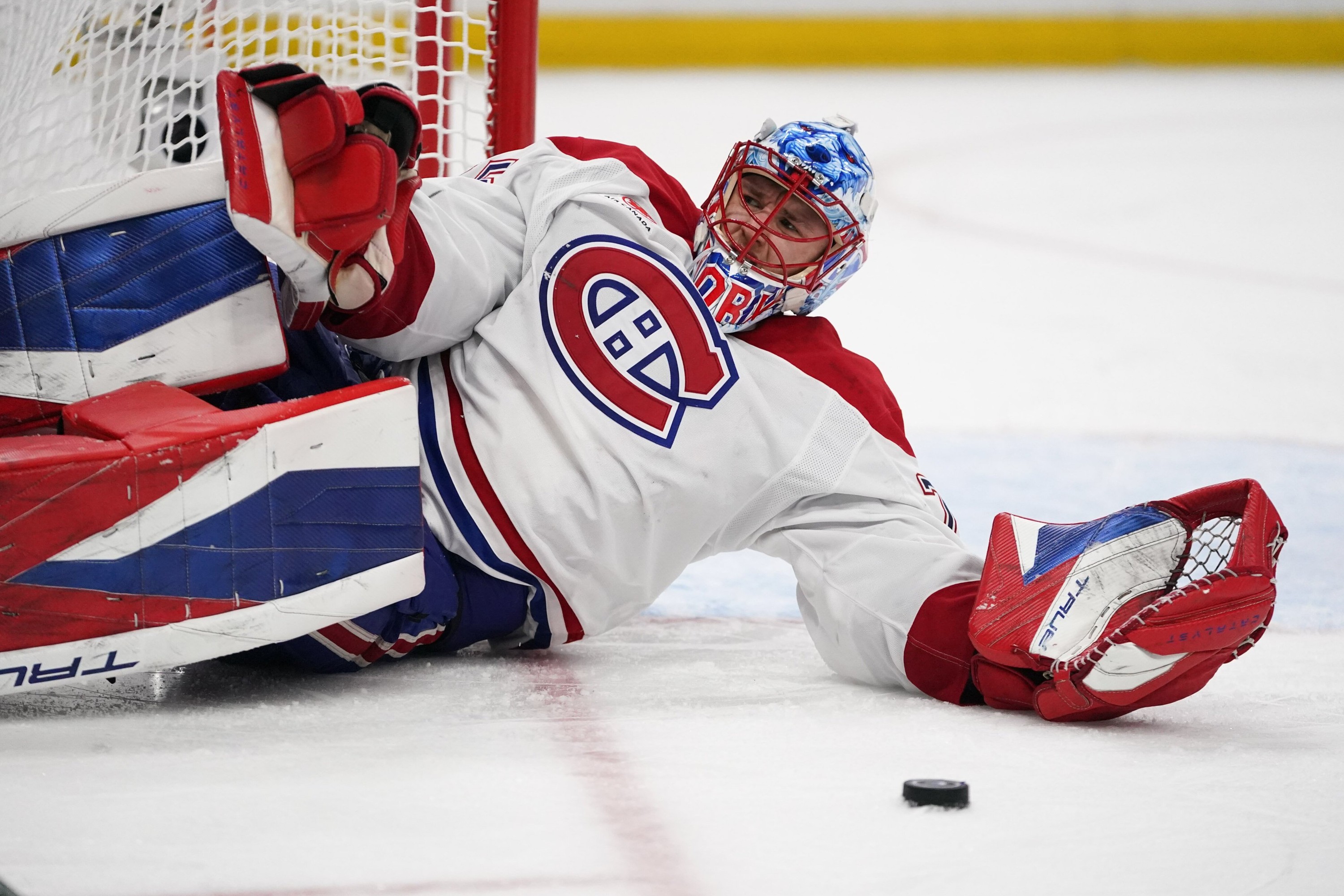 Jakub Dobes is lying on the ice next to the crease with the puck in front of him
