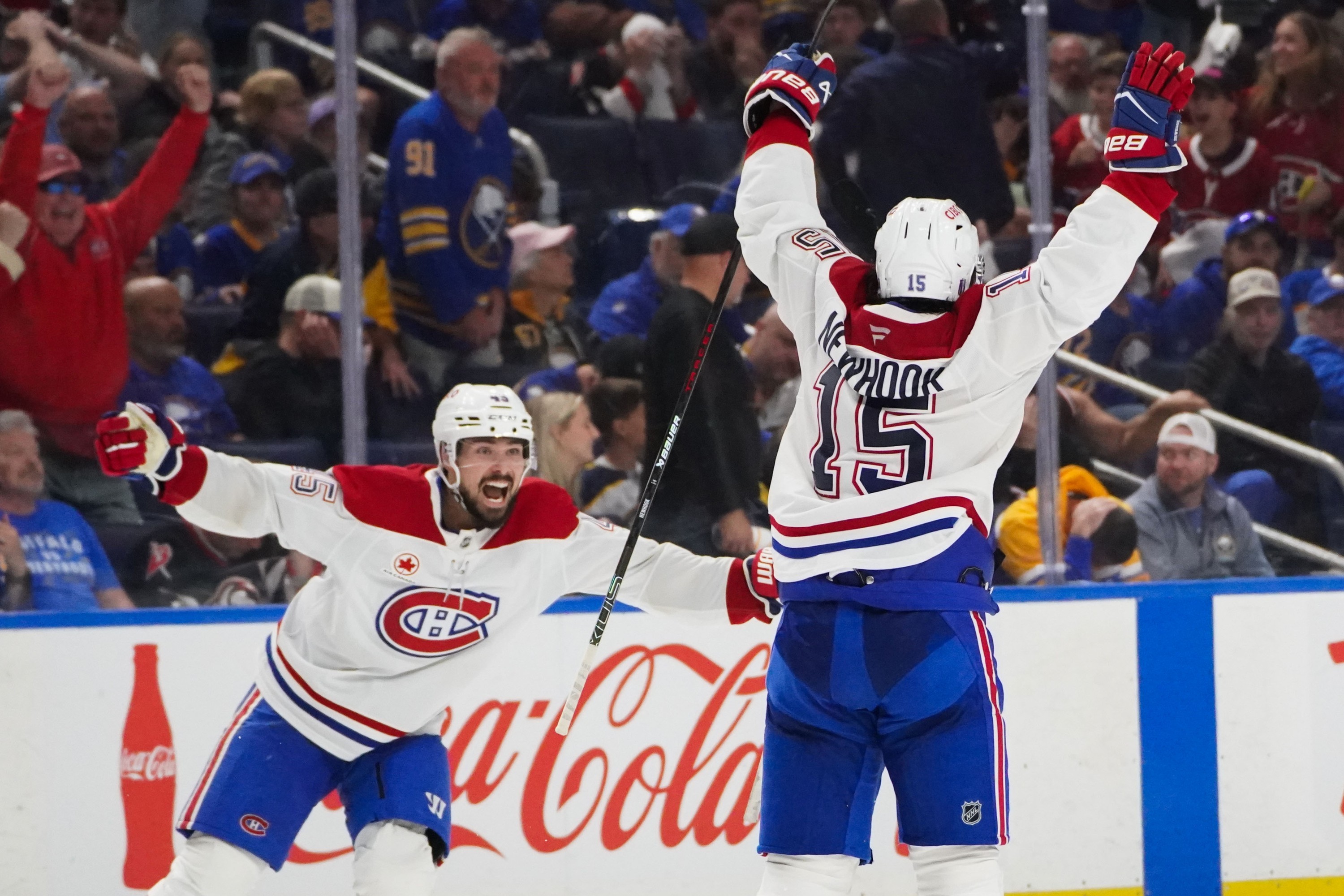 Montreal Canadiens centre Alex Newhook (15) throws his arms up in celebration as Alexandre Carrier skates toward him on the ice