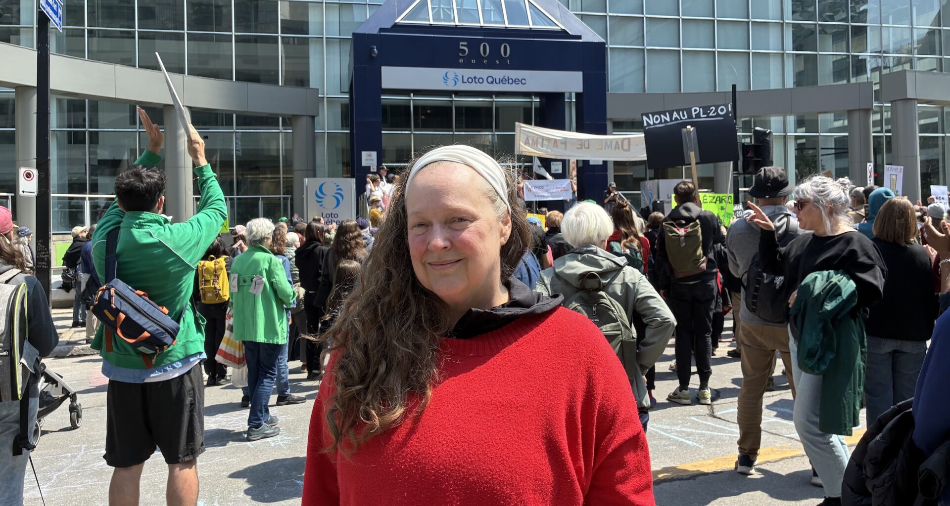 Heidi Miller poses for a photo in front of a protest outside a downtown building.
