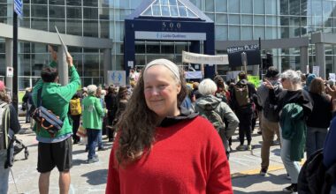 Heidi Miller poses for a photo in front of a protest outside a downtown building.