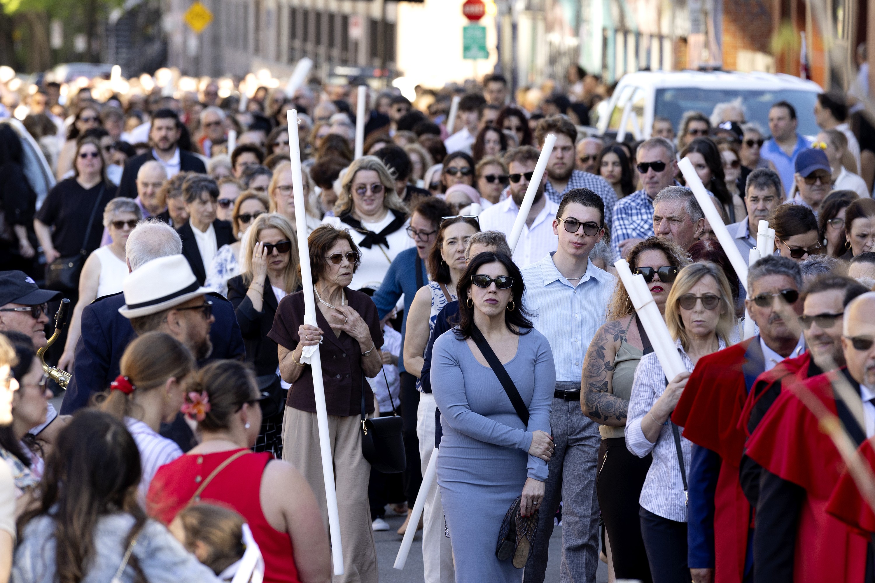 A large crowd of people take part in an outdoor procession.