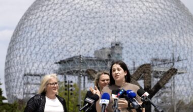 A woman speaks in front of a bank of media microphones as two other women listen behind her, as the trio stand in front of Montreal's Biosphère.