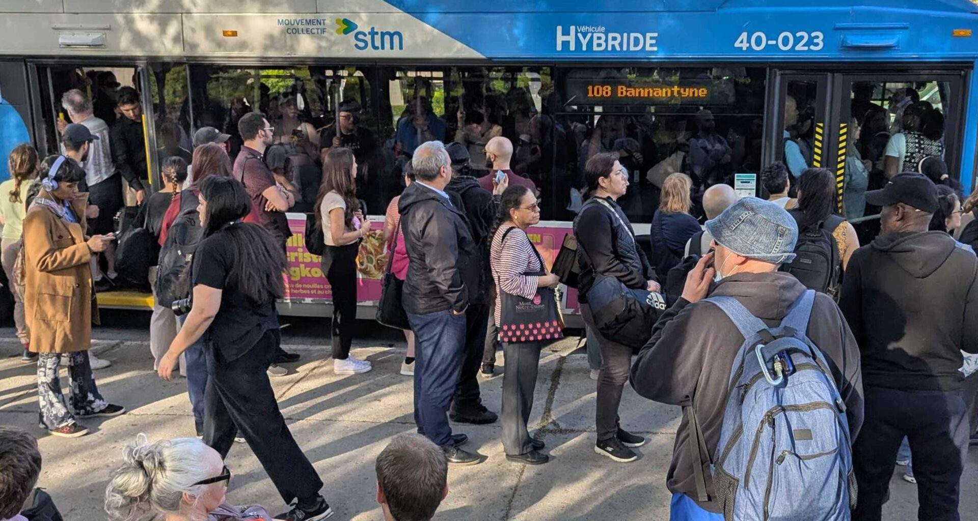 People line up next to a jam-packed bus.