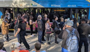 People line up next to a jam-packed bus.