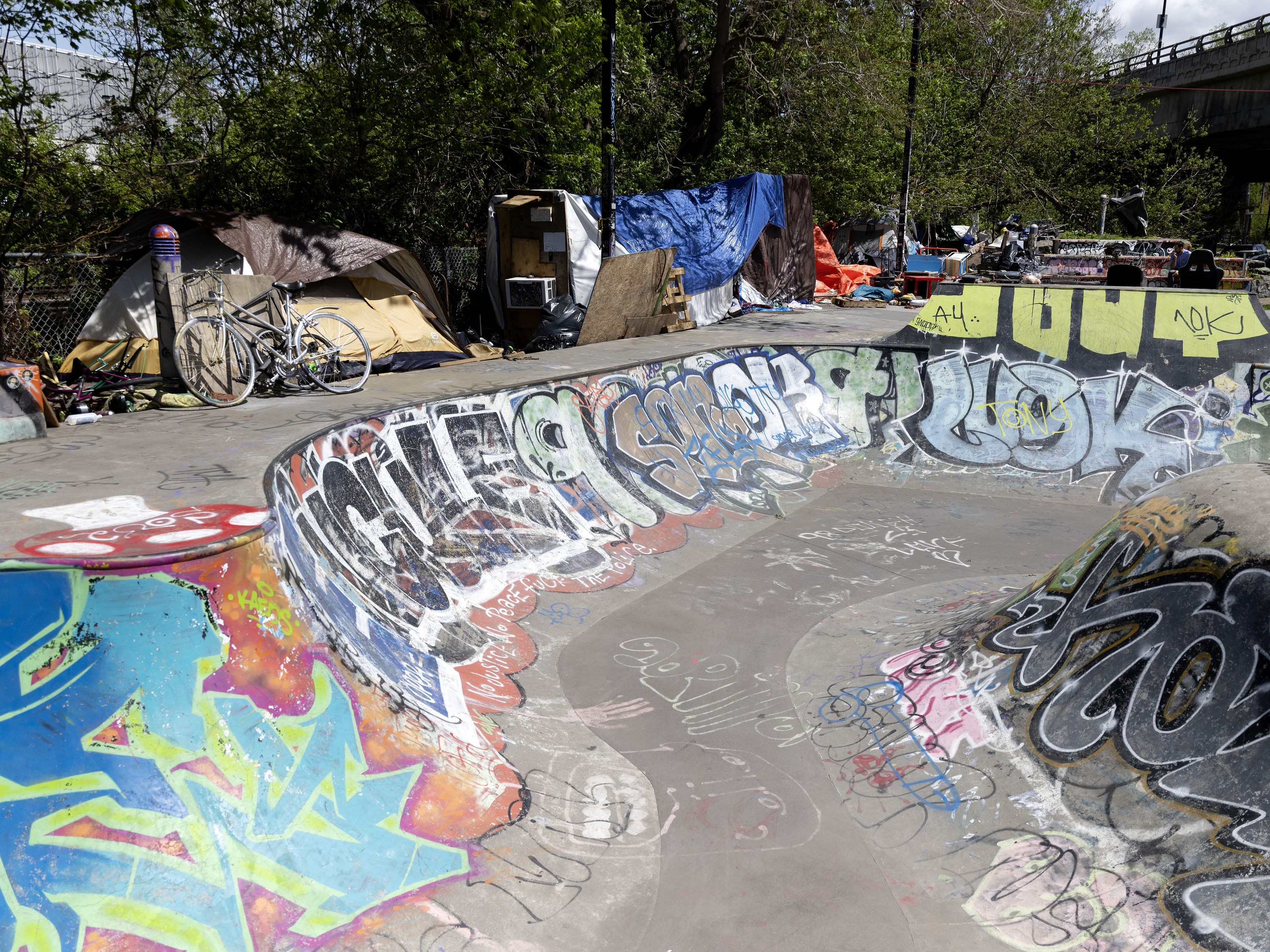 A homeless encampment beside a skatepark covered in grafitti.