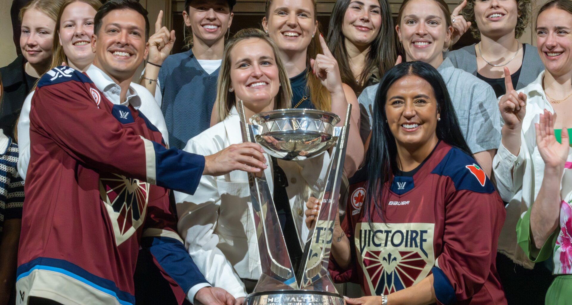 Laval Mayor Stéphane Boyer and Montreal Mayor Soraya Martinez Ferrada flank Victoire captain Marie-Philip Poulin with the Walter Cup, with teammates behind them.