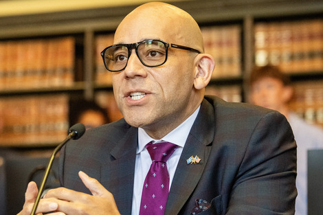 Man sits at table, speaking into mic
