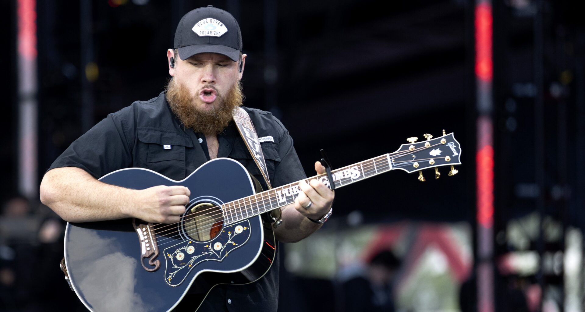 Country musician with a beard plays guitar in concert.
