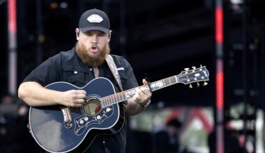 Country musician with a beard plays guitar in concert.