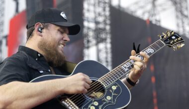 Luke Combs grimaces as he plays guitar.