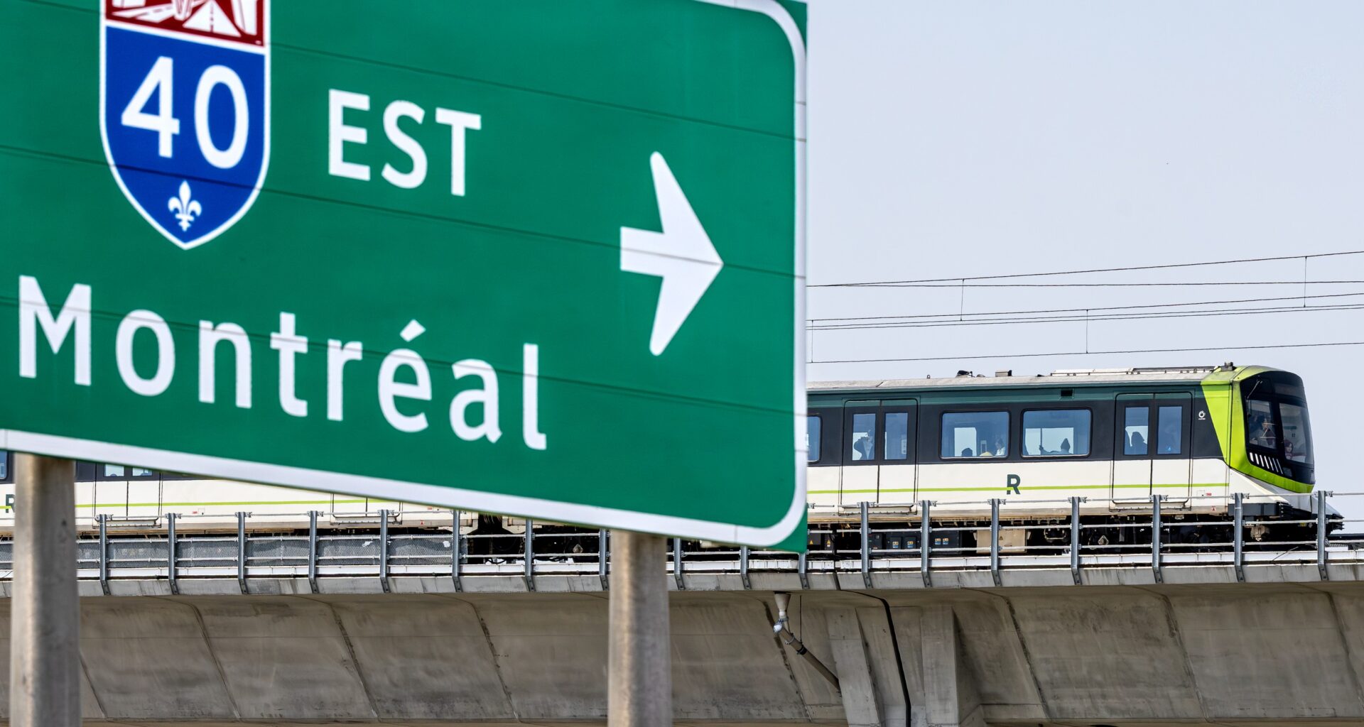 REM train on elevated platform travels by Highway 40 / Montreal sign