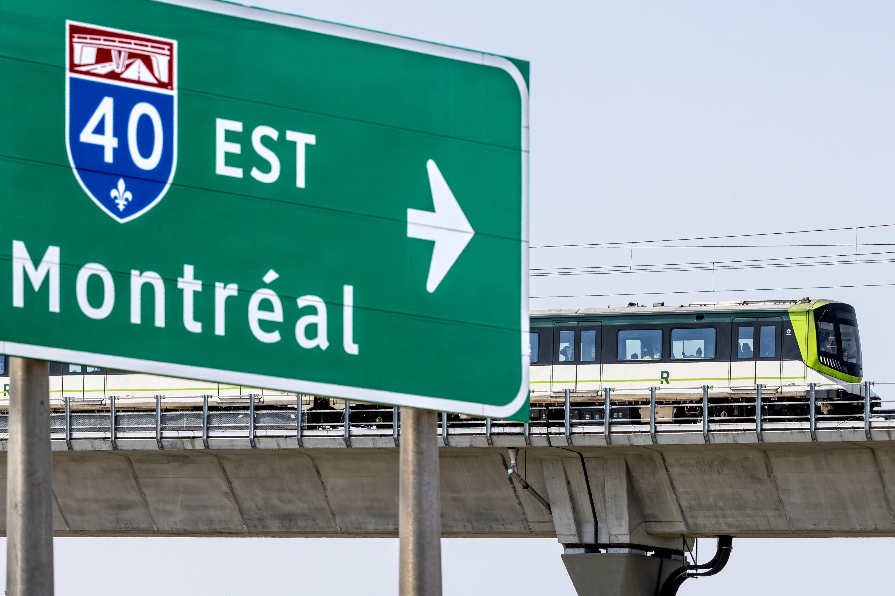 REM train on elevated platform travels by Highway 40 / Montreal sign