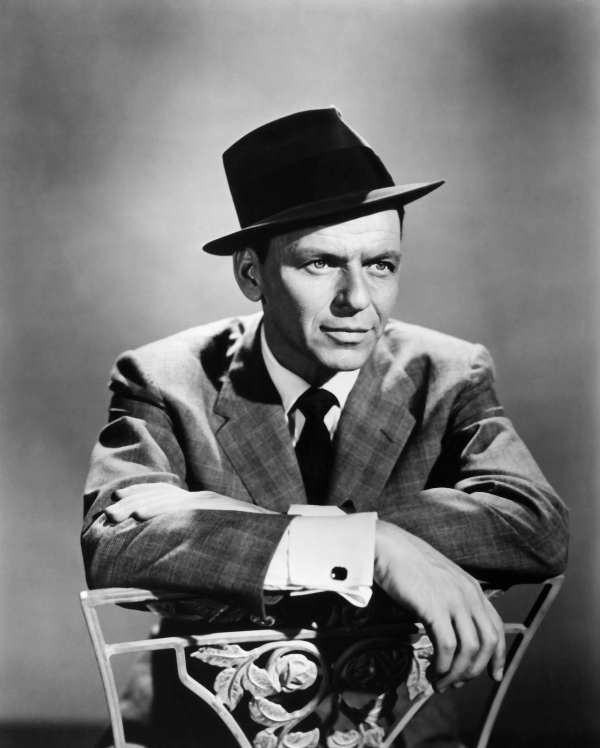 Frank Sinatra strikes a classic Rat Pack pose in fedora hat for 1950's studio publicity portrait.