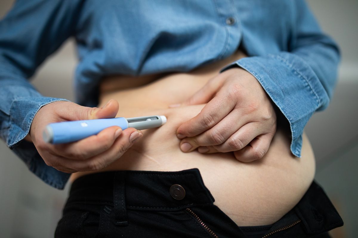 Close-up image of an individual administering a semaglutide injection into their abdomen for weight loss and obesity management. A personal moment showcasing modern medical solutions for health improvement.