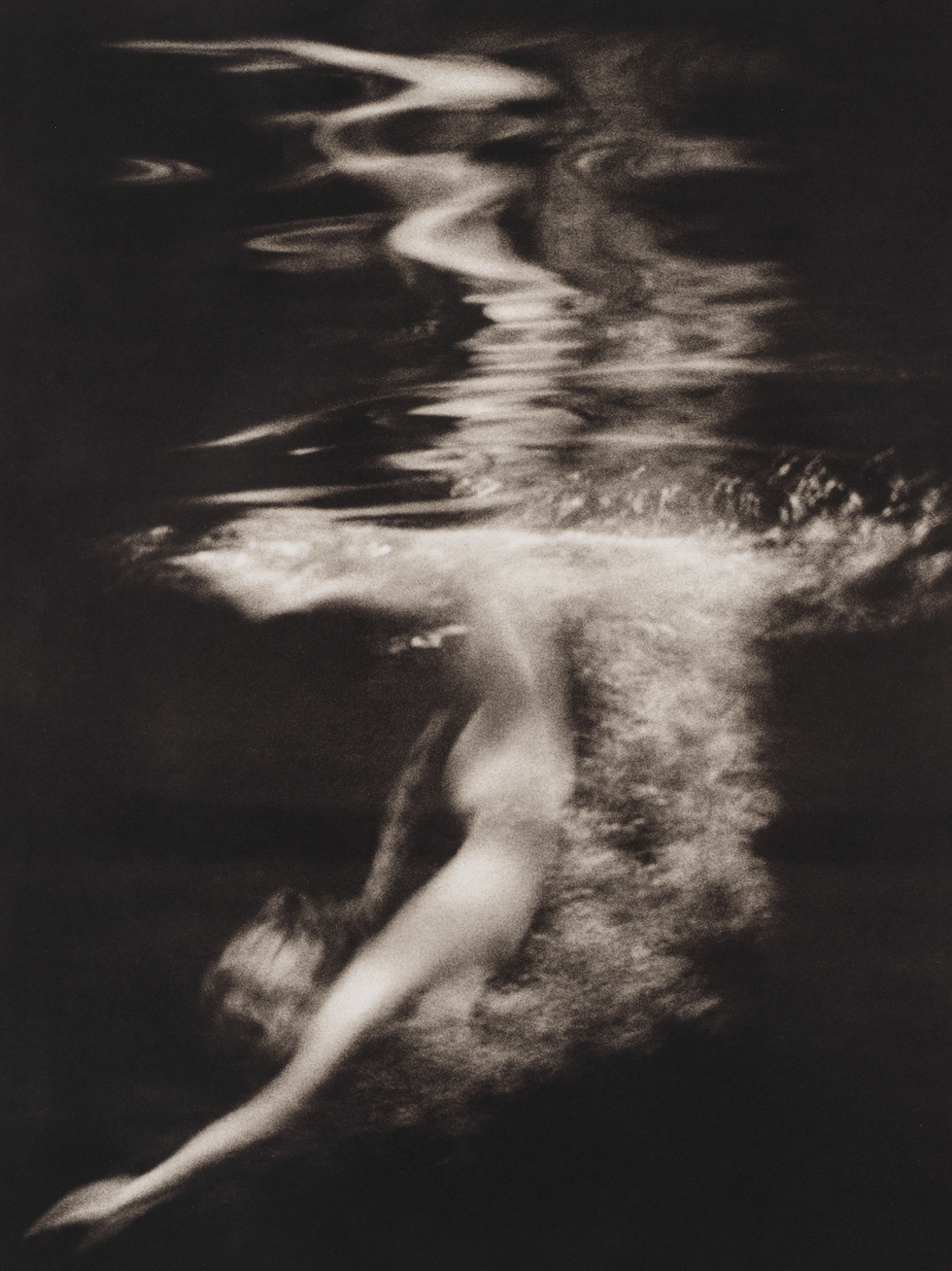 A submerged figure creating ripples in dark water.