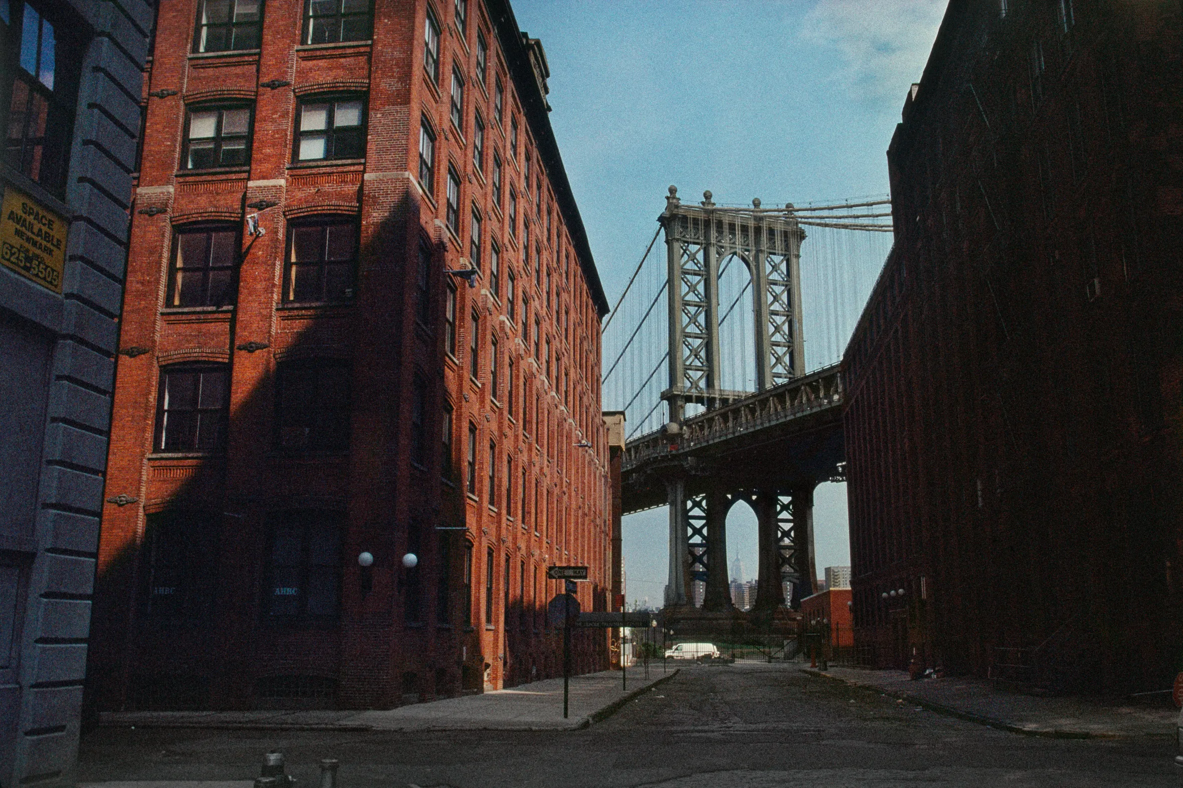 View of the Manhattan Bridge in New York City framed by brick buildings.