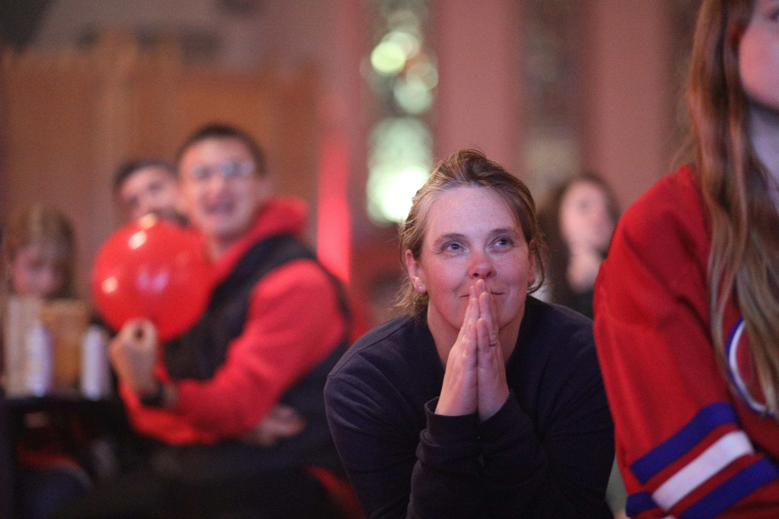 Woman watching hockey game with hands in prayer