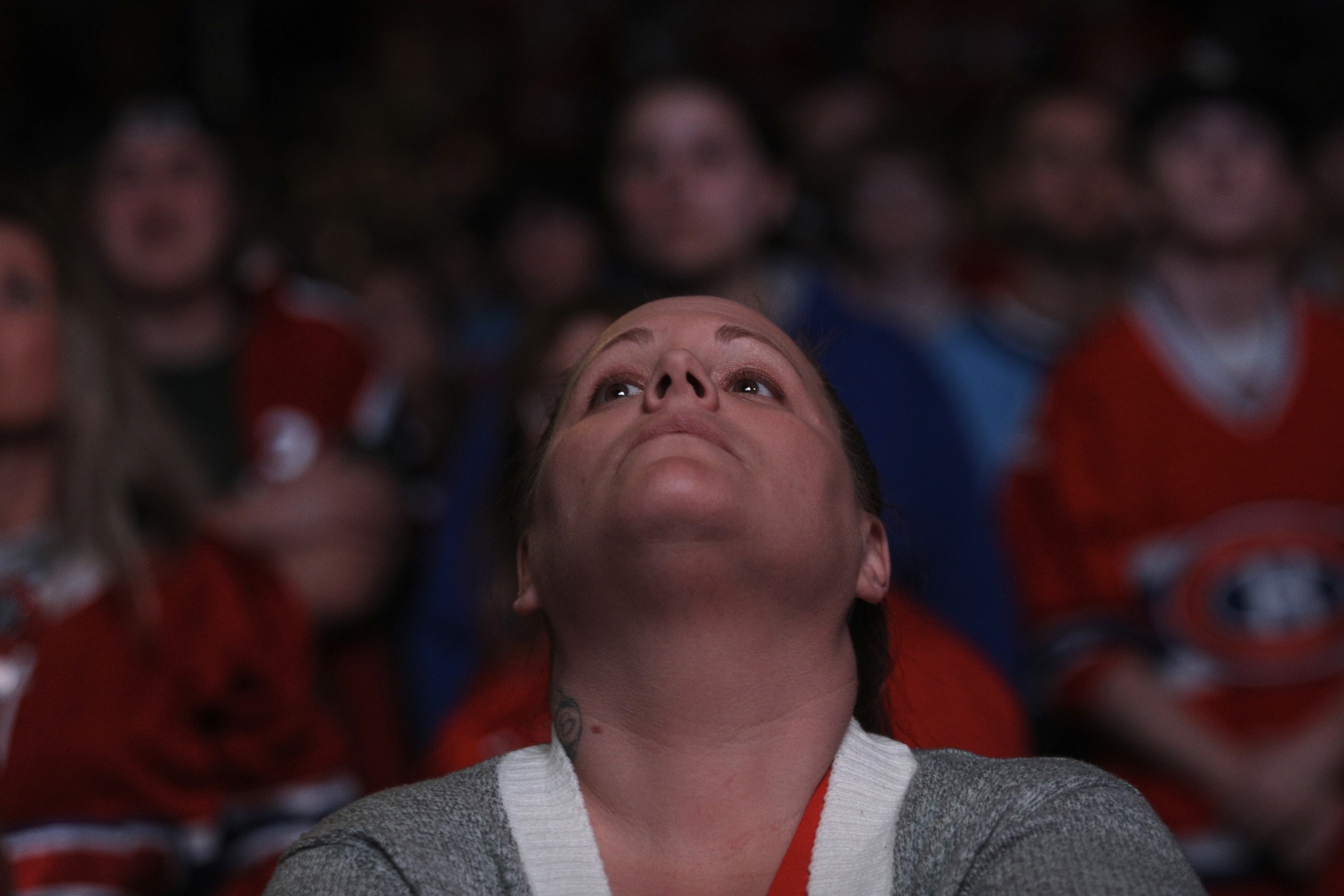 A woman cranes her head back at the front of a crowd of Montreal Canadiens fans.