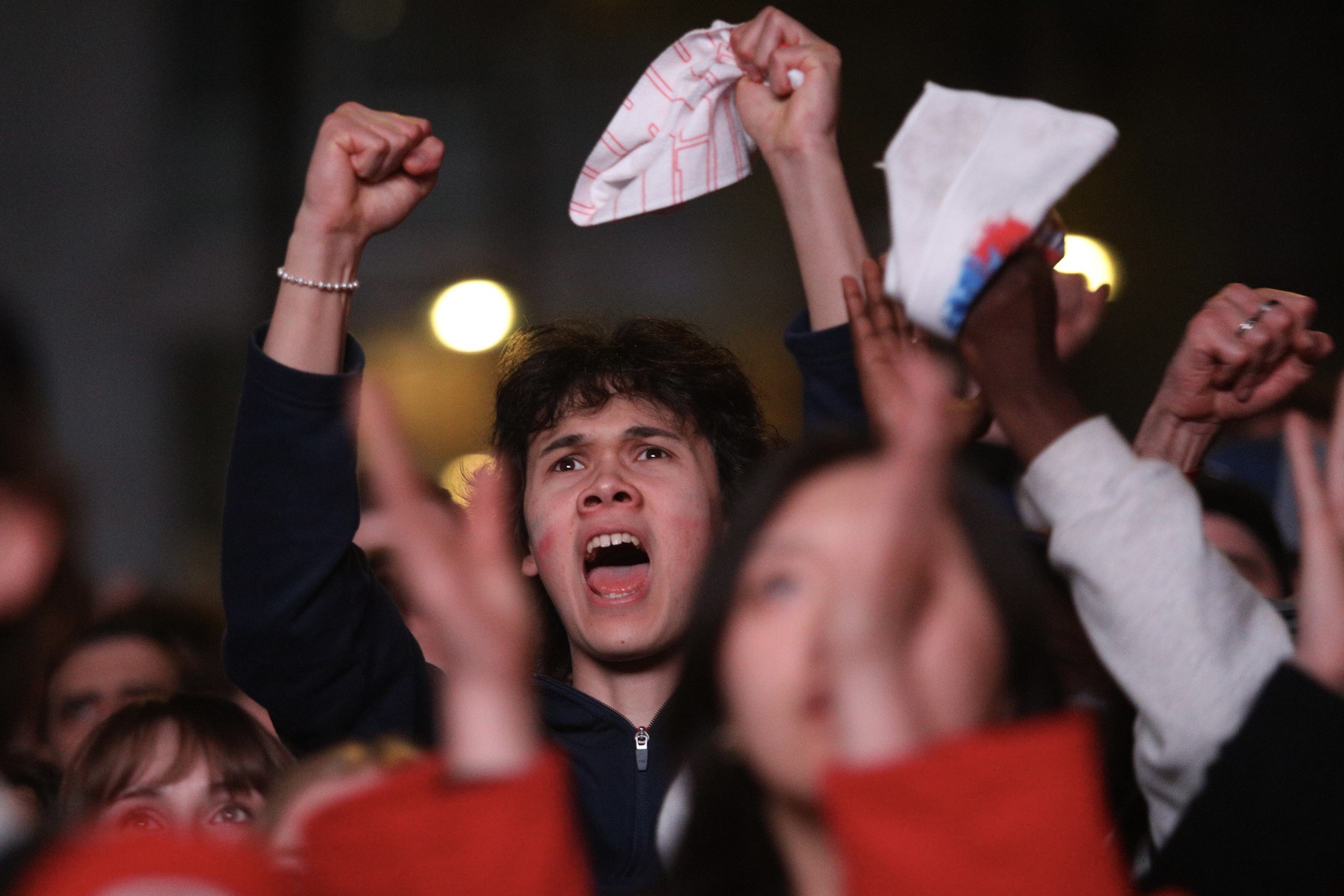 A fan cheers at an outdoor Montreal Canadiens watch party, surrounded by other fans.