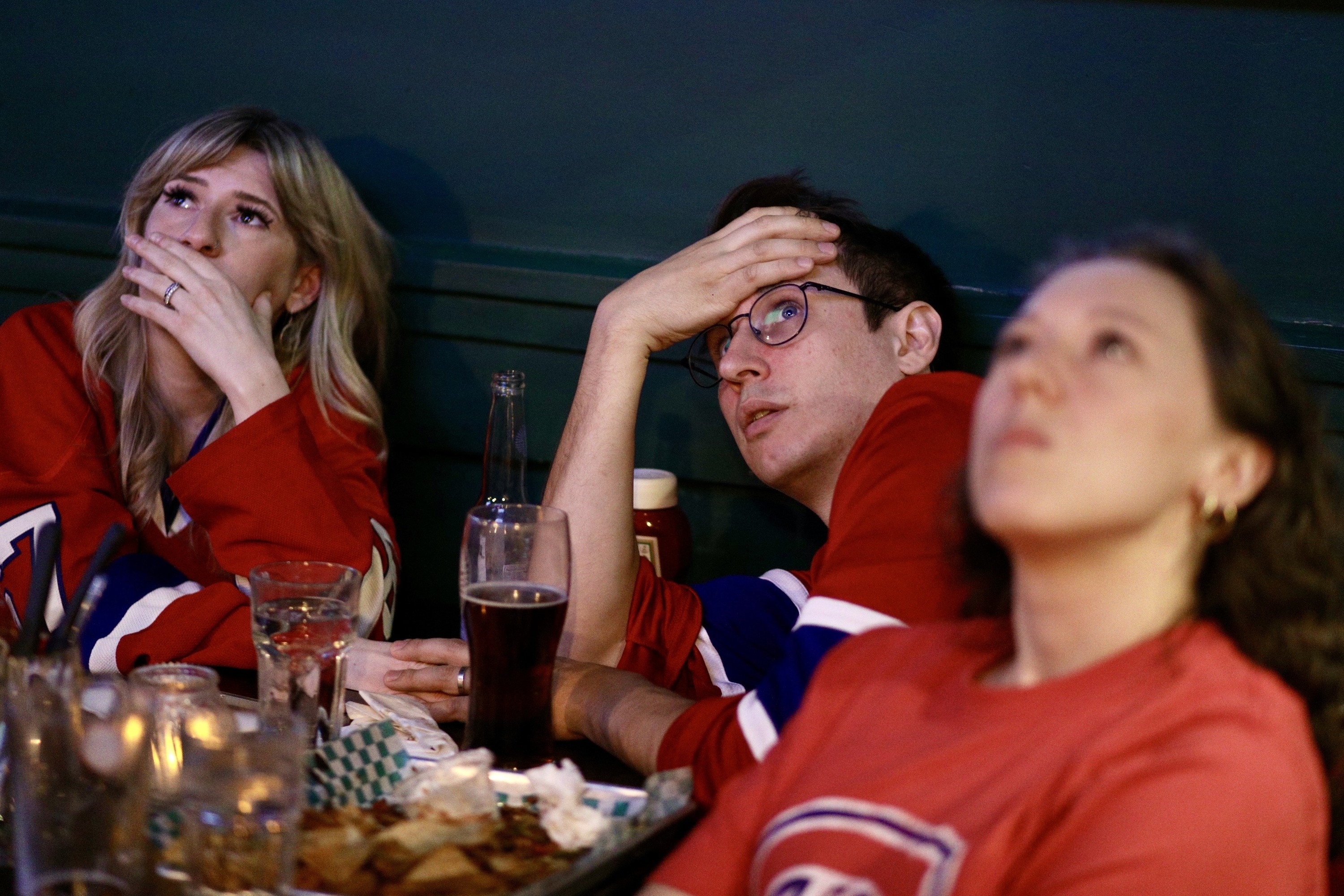 Hockey fans are dejected watching the game at a bar.