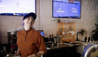 A woman laughs behind the counter at a sports bar.