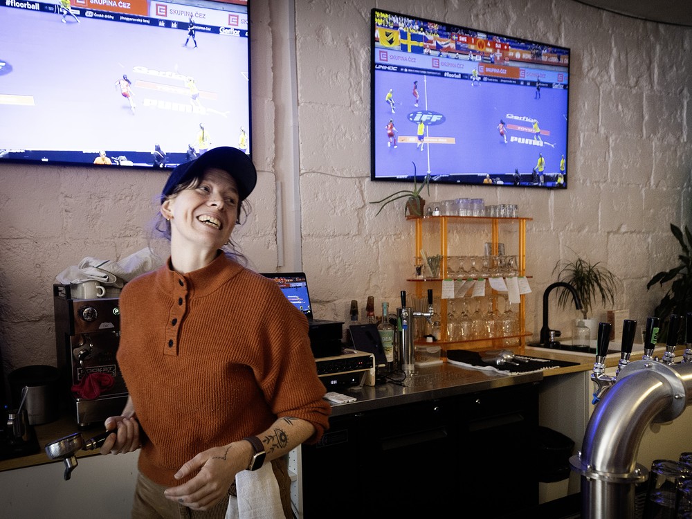 A woman laughs behind the counter at a sports bar.