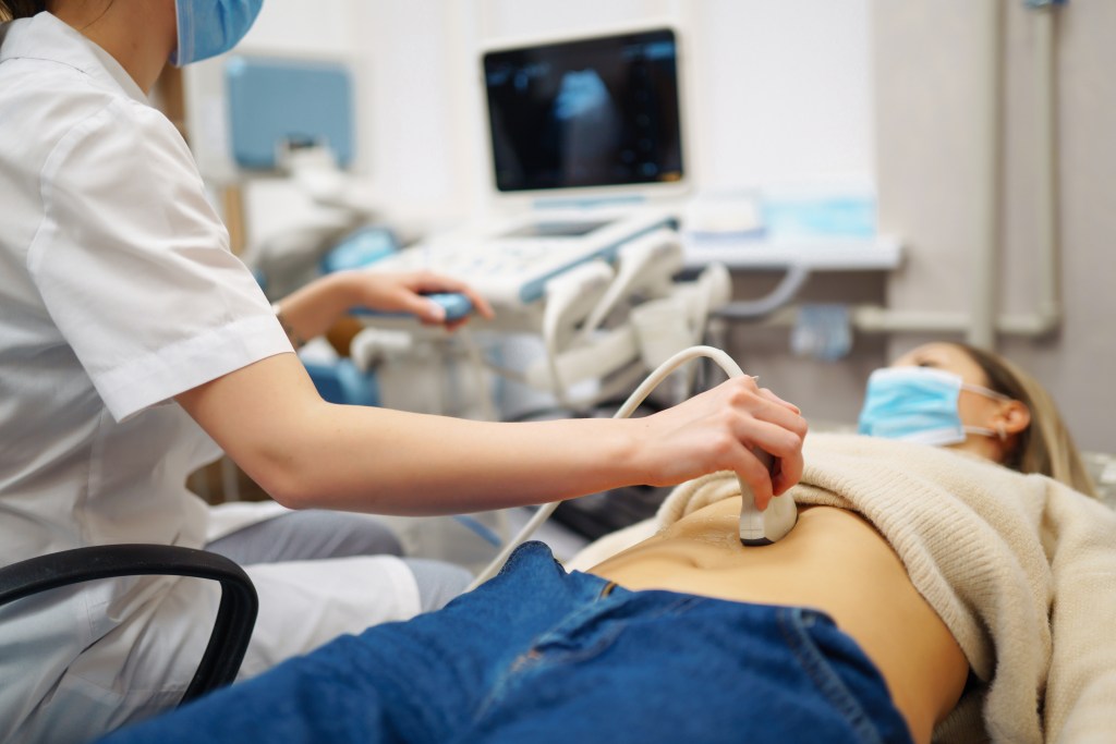 Doctor performing an abdominal ultrasound on a patient.