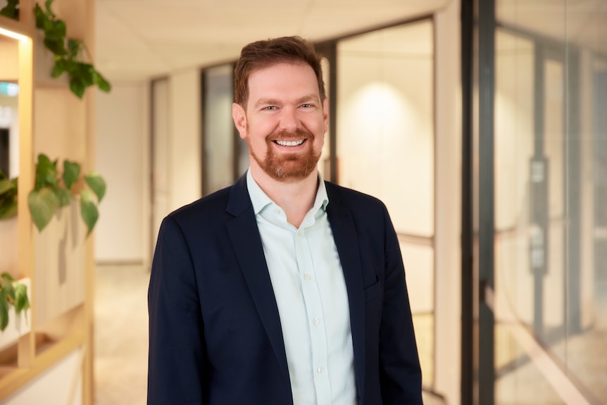 Man in suit smiles at camera in office building