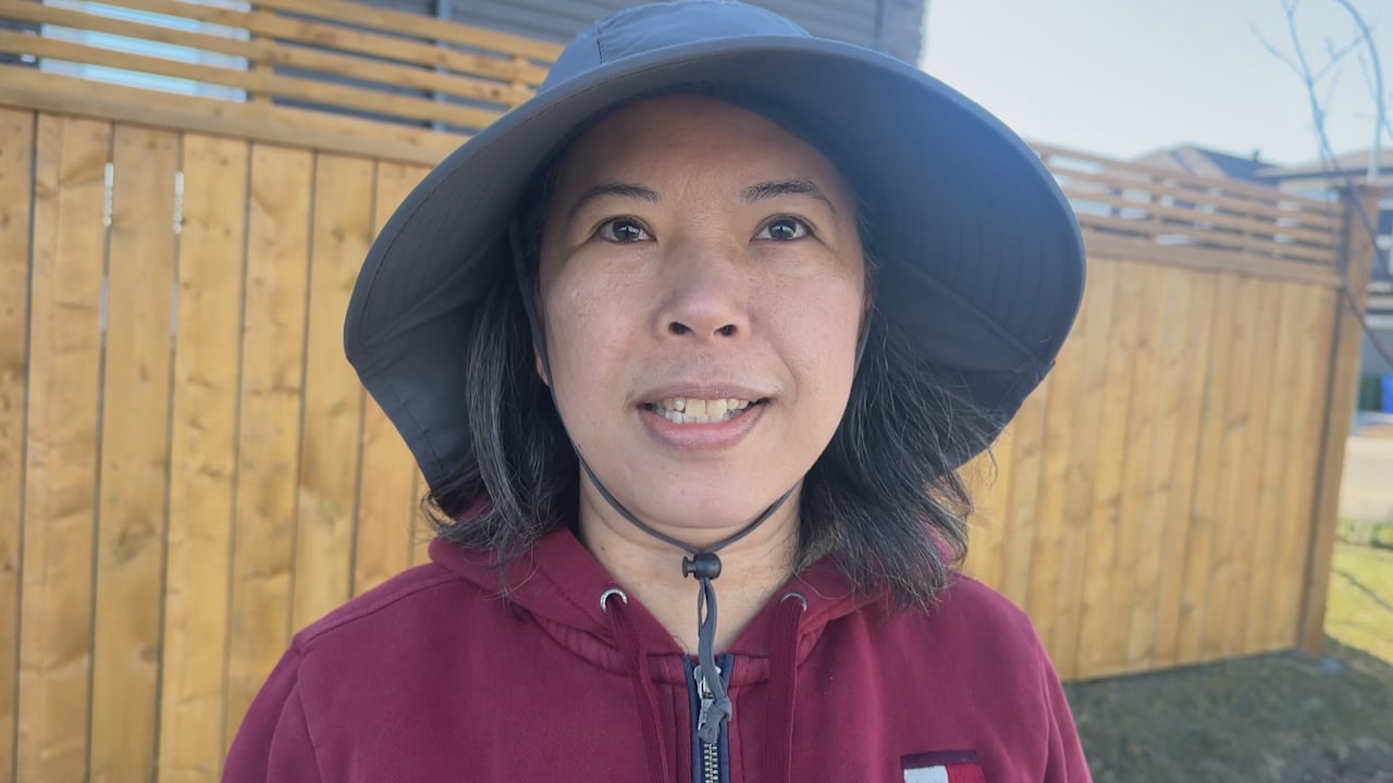 A woman wearing a sunhat looks at a reporter off camera.