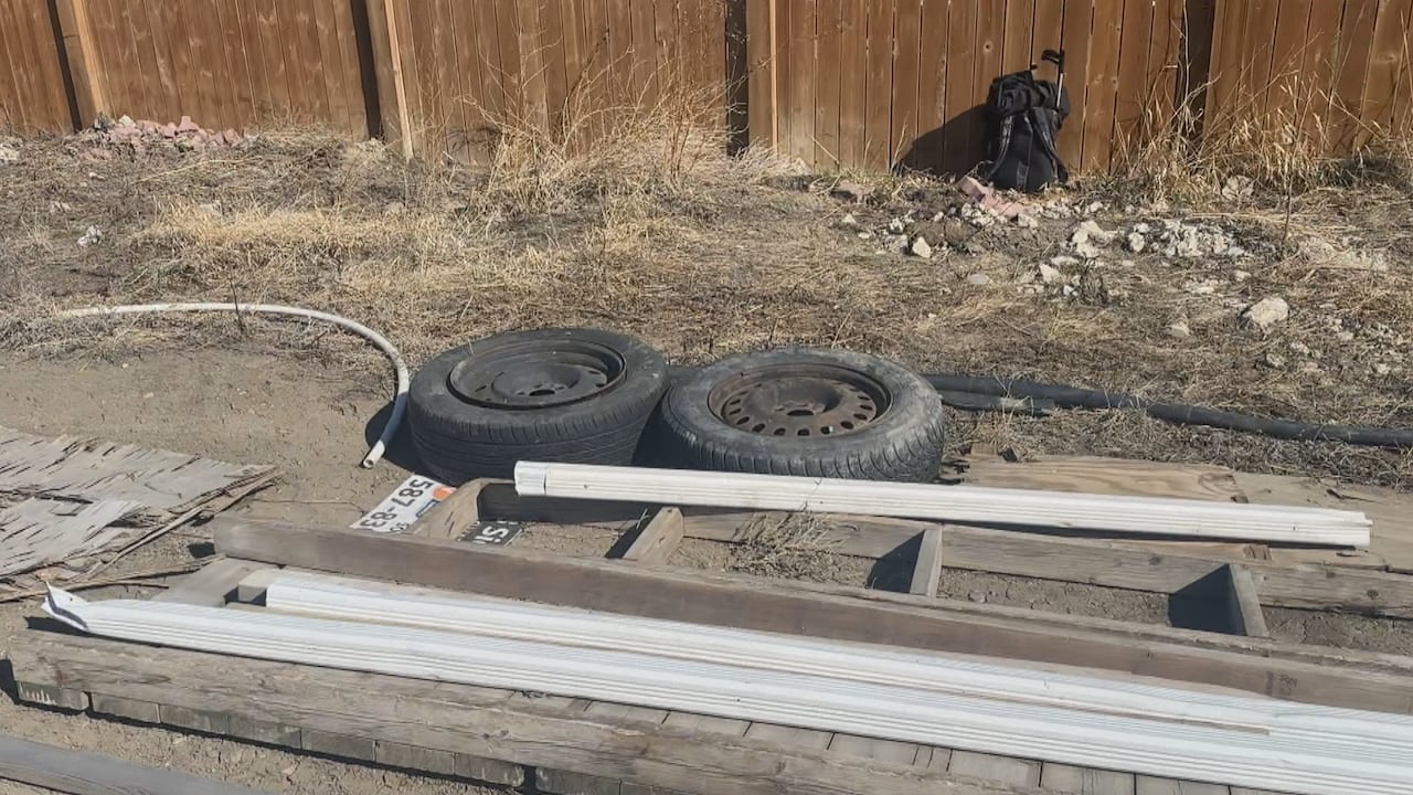 Old tires, construction materials and garbage bags lay discarded in a field.
