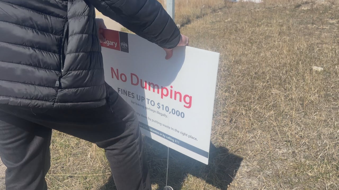 A man pushes a lawn sign into the ground.