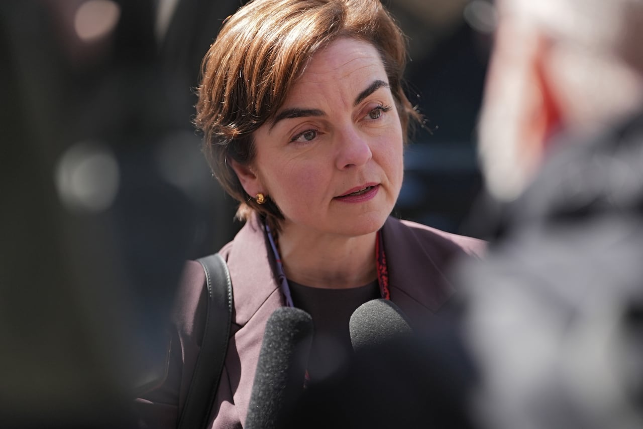 A woman speaks with reporters