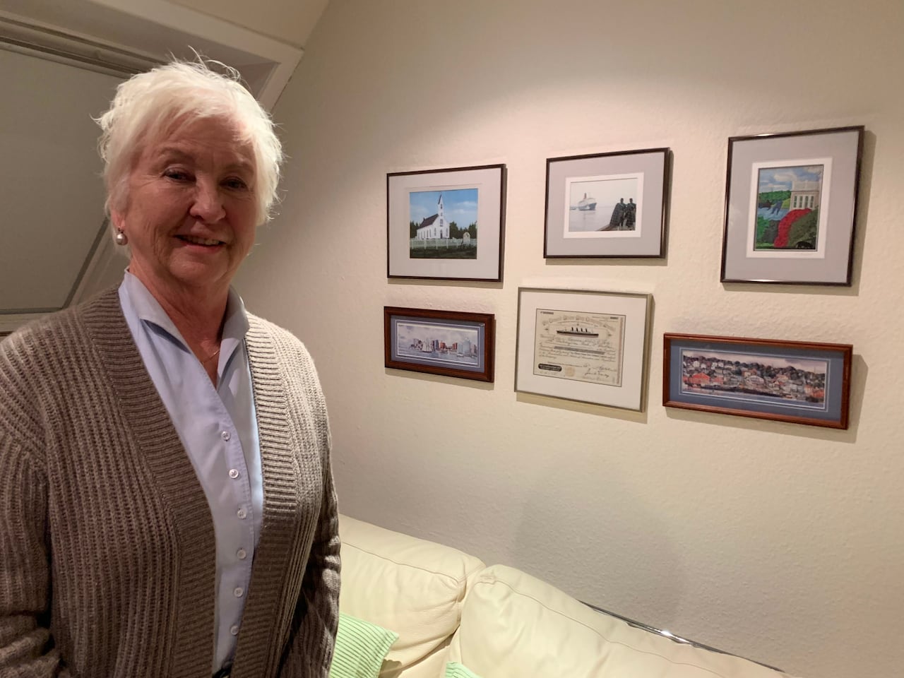 A woman stands in front of a wall with photos.