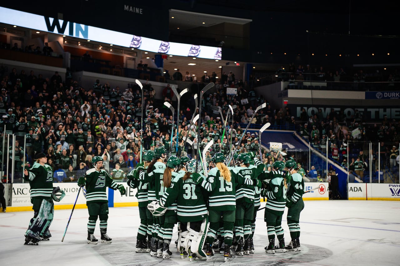 A hockey team celebrates on the ice after a win.