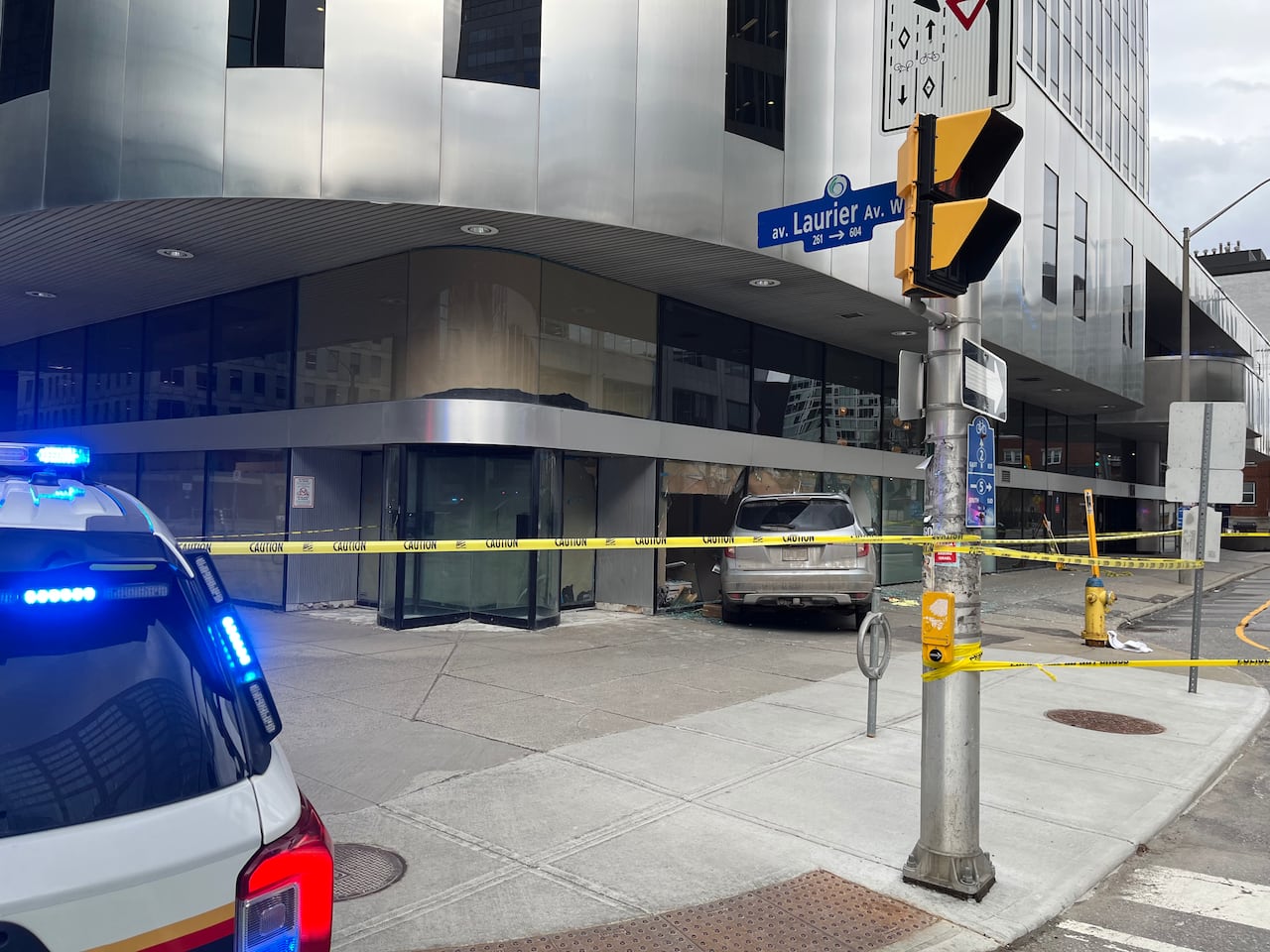 a grey vehile crashed into a window pane with a blue sign that reads Laurier