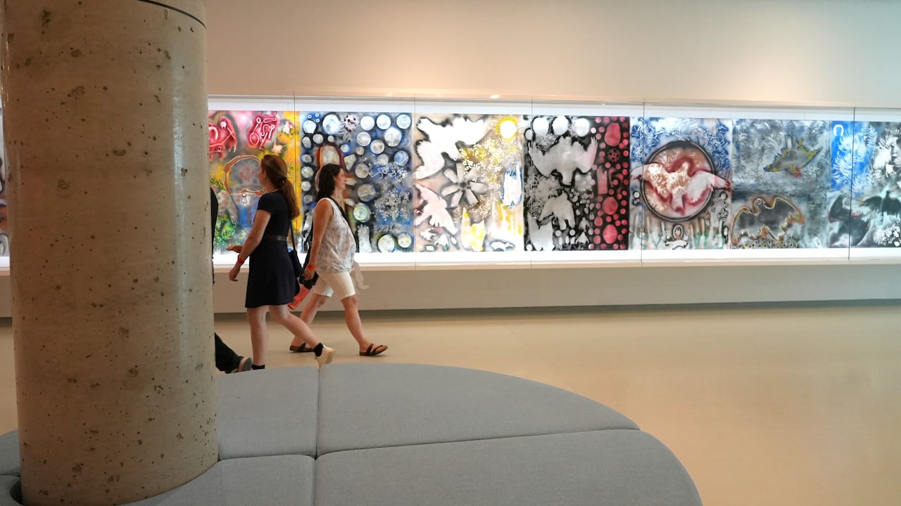 People walking in front of artwork